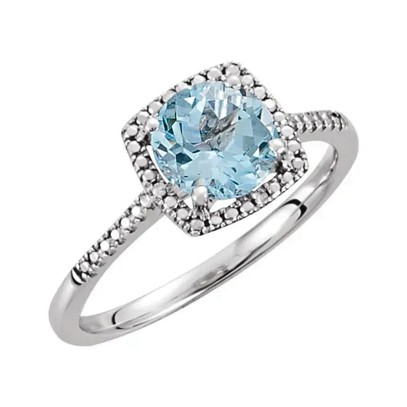 A top view of the Sky Blue Topaz and Diamond Halo Style Birthstone Ring showcasing the vibrant 7mm sky blue topaz surrounded by a beaded halo of four sparkling diamonds set in rhodium-plated sterling silver. Available from Jewels of St Leon.