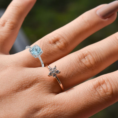 A close-up shot of the Sky Blue Topaz and Diamond Halo Style Birthstone Ring on a model's finger, highlighting the brilliant topaz and diamond accents against the tarnish-resistant sterling silver band.