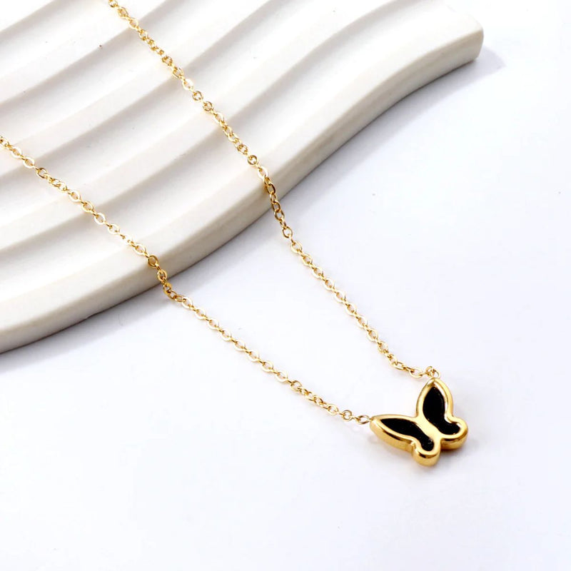 The Black Butterfly Necklace draped gracefully down a stepped display, highlighting the sleek contrast between the black enamel and warm 18K gold finish.