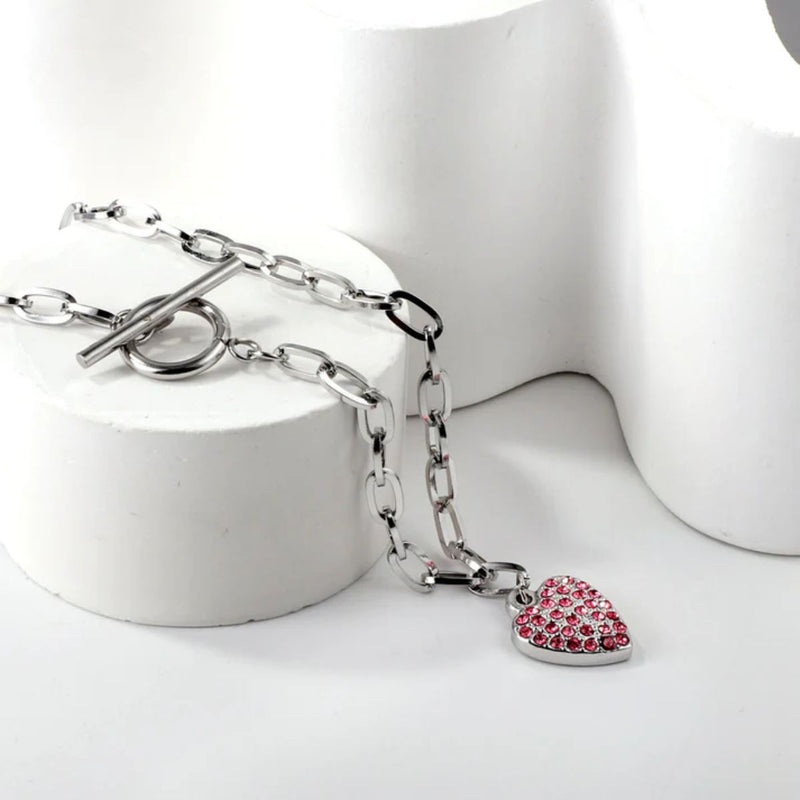 Pendant necklace draped down a round display stand, showing the bold shape and effortless flow of the polished silver chain.