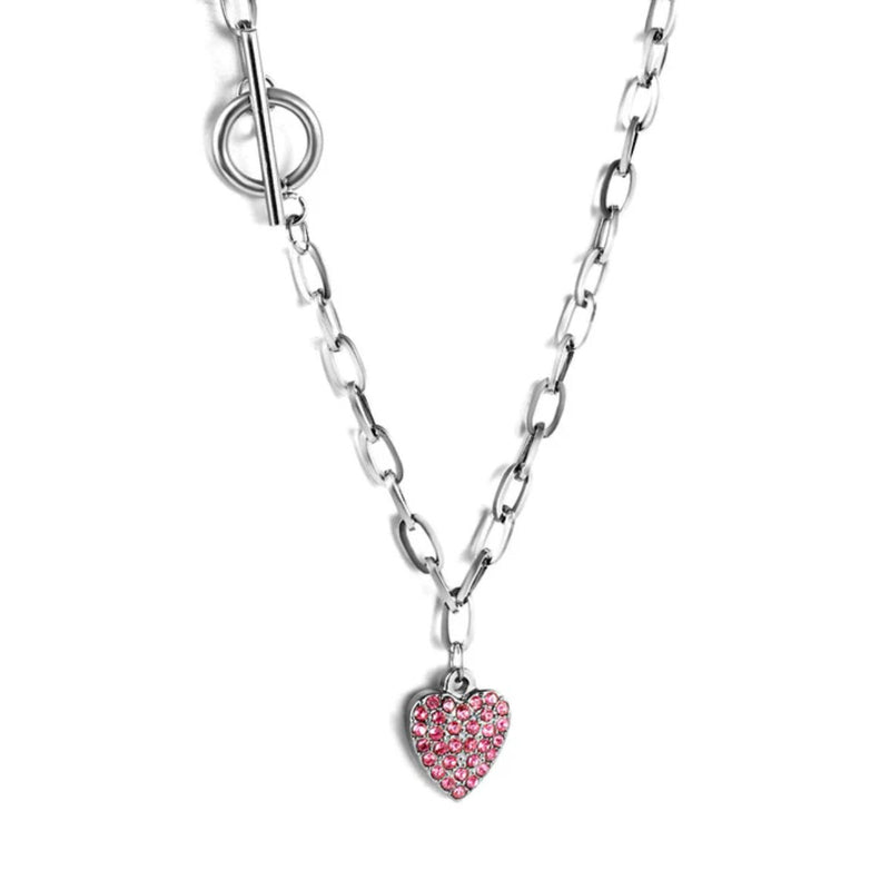 Close-up of the silver heart pendant with pink CZs, toggle clasp and bold paperclip chain — capturing the shimmer and polished finish.