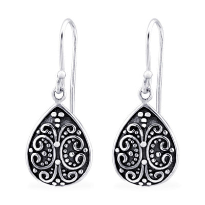 Close-up of sterling silver oxidised teardrop filigree dangle earrings, showing detailed swirling pattern and darkened antique finish.