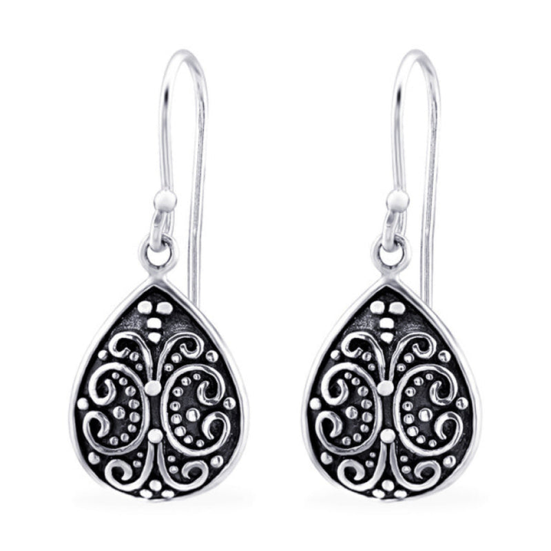 Close-up of sterling silver oxidised teardrop filigree dangle earrings, showing detailed swirling pattern and darkened antique finish.