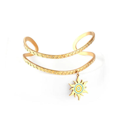 A bold cuff bracelet featuring a detailed saw-tooth pattern and a radiant sun pendant in polished 18K gold-plated stainless steel.