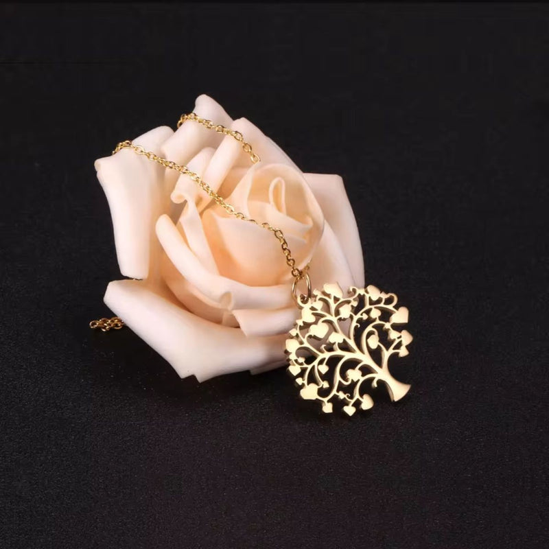 Tree of Life Necklace draped across a peach rose on a black background, creating a striking contrast and evoking warmth, love, and nature’s beauty.