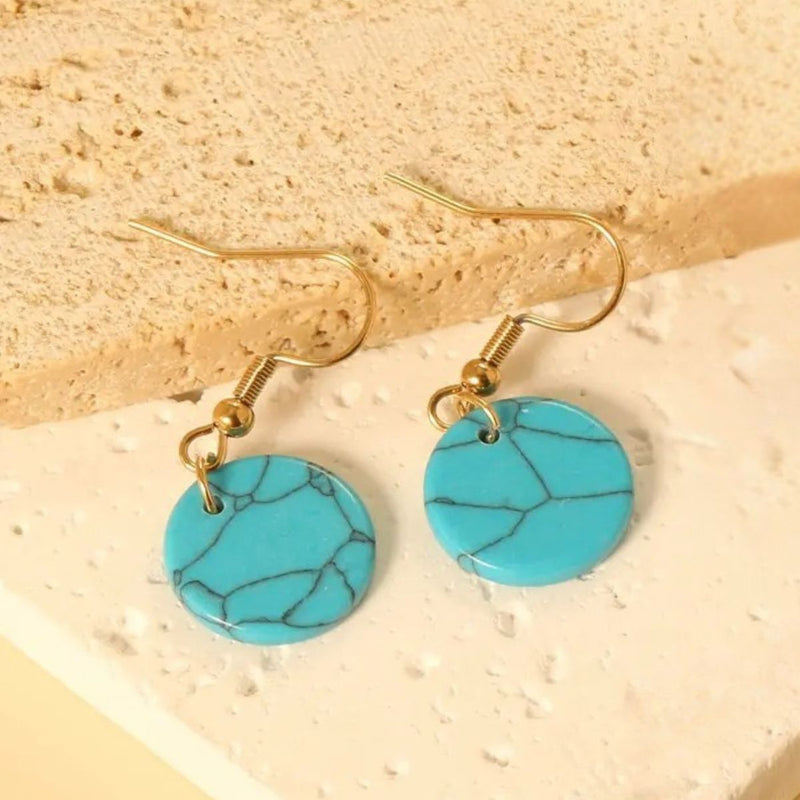 Turquoise Style Earrings resting on a soft fabric backdrop, capturing the bold colours and sleek, trendy design perfect for everyday wear.