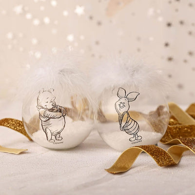 Winnie the Pooh and Piglet Disney collectible Christmas bauble set with feathers and gold ribbon on a festive background.