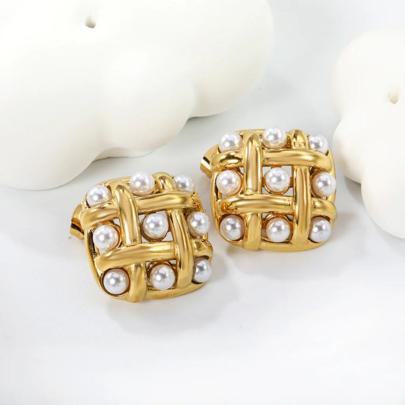Overhead set-up of woven gold pearl earrings beside minimalist ceramic shapes, emphasising modern square silhouette and scattered pearls.
