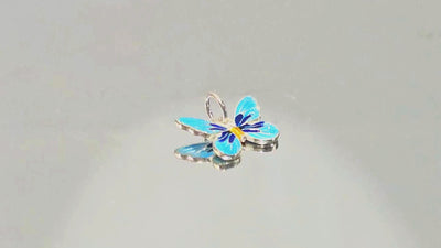 Blue Enamel Silver Butterfly Charm Pendant Video: Experience the beauty of our Silver Blue Enamel Butterfly Charm Pendant. Featuring vibrant light and dark blue tones with gold accents, this nature-inspired sterling silver charm adds a touch of elegance and whimsy to any jewellery collection.